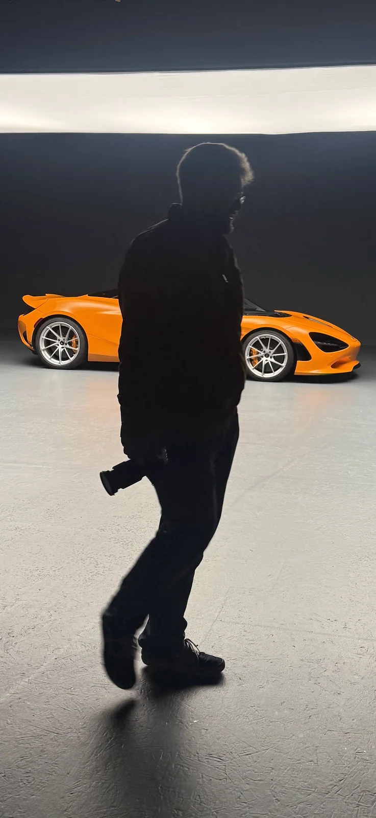 Max McCord in silhouette with his camera in the studio